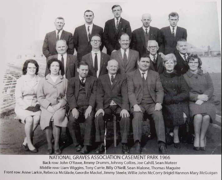 Group photograph of the National Graves Association Casement Park, taken in 1966. The image features two rows of people, a mix of men and women, dressed in formal attire. The back row consists of men standing, while the front row consists of seated individuals, including women and men.
